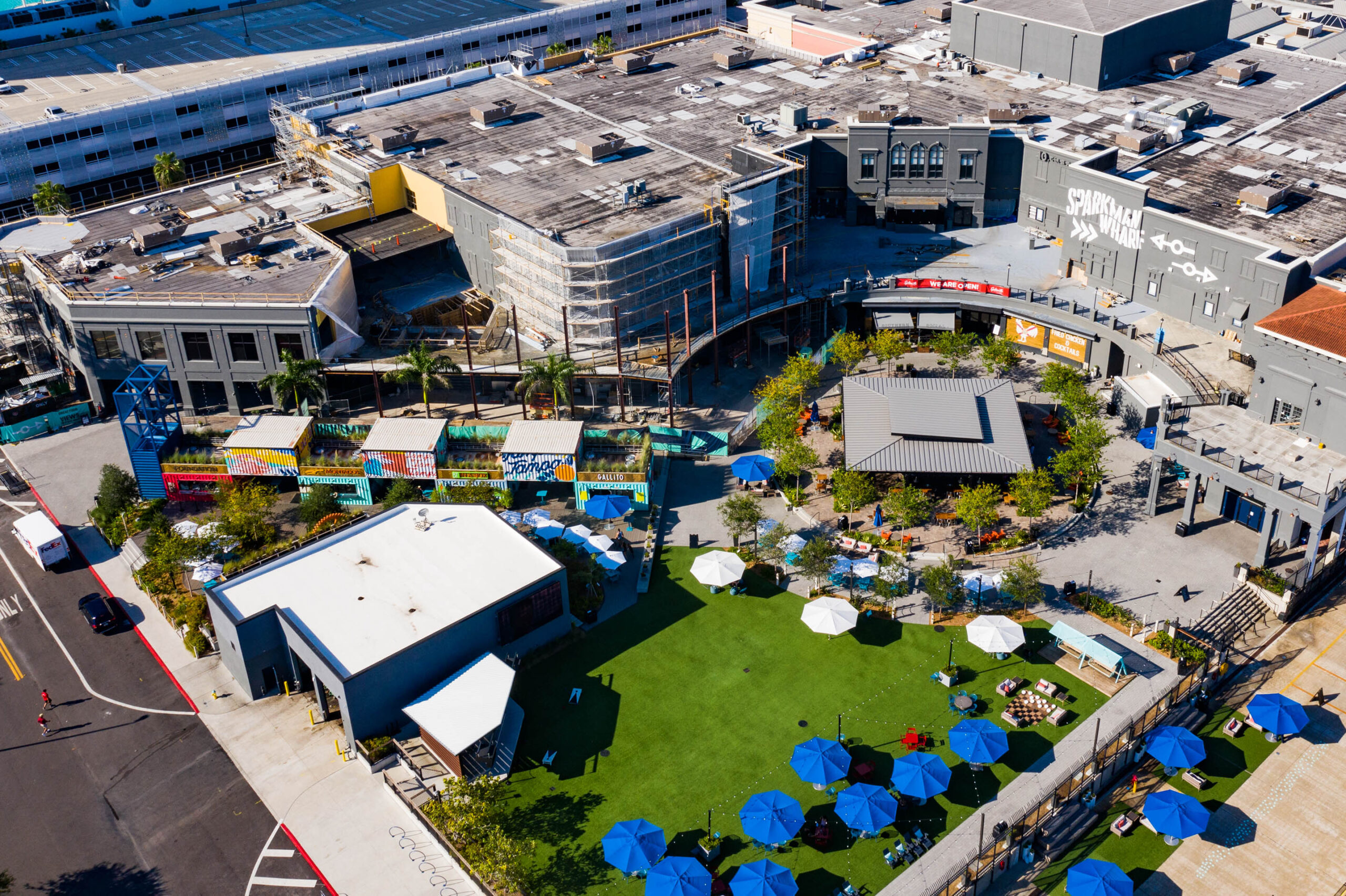 Aerial view of Sparkman Wharf at Water Street Tampa with shipping container murals, lawn and blue umbrellas